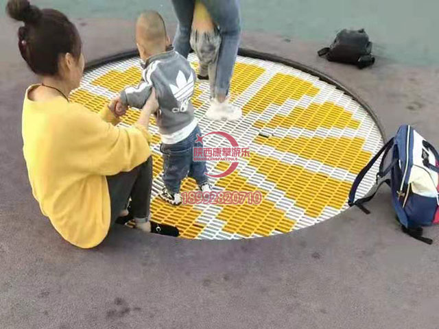 大人領小孩在地埋蹦床上玩耍